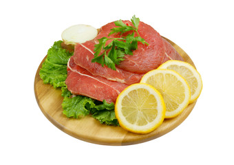 Raw beef meat with lemon and greens