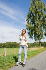 Inline skating young woman on sunny asphalt road