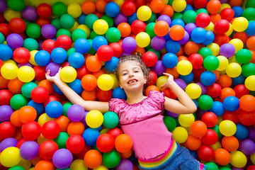 Fototapeta na wymiar child girl on colorful balls playground high view