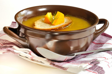 zupa dyniowa w glinianym garnku na białym tle