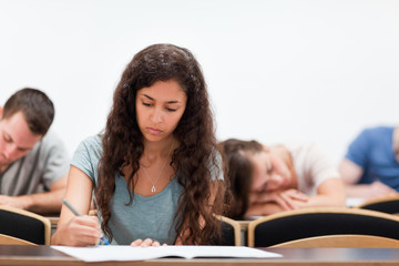 Fototapeta na wymiar Students writing while their classmate is sleeping
