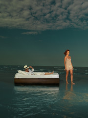 young couple laying bed surrounded by sea