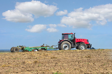 Fototapeta na wymiar Tractor with cultivator handles field before planting