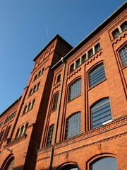 Sanierte Backstein Fassade einer alten Fabrik der Gründerzeit vor blauem Himmel im Sonnenschein in...
