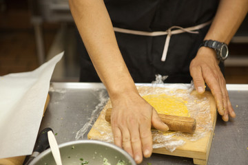 professional cook rolling dough on wood surface