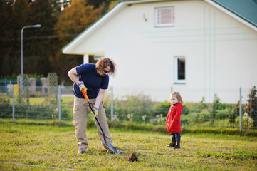 A man shovels a hole in the yard, preparing to plant a tree