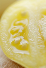 One sliced yellow tomato on chopping board.