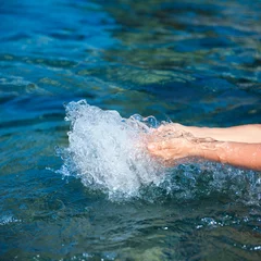 Fototapeten Hands splashing pure water from blue sea. © Evgeniya Moroz