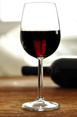 Glass and bottle of fine Italian red wine on a table in oak
