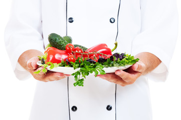 chef holding plate with vegetables