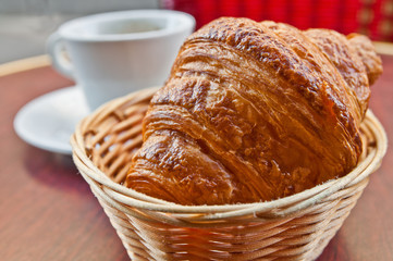 Breakfast with coffee and croissants in a basket on table