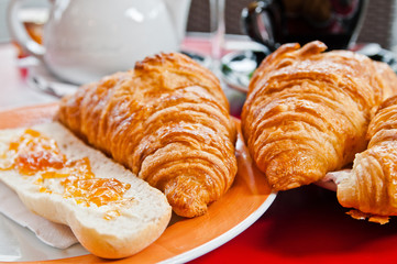 Breakfast with coffee and croissants in a basket on table