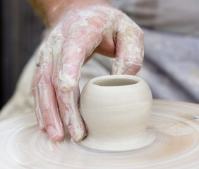 Artisan make a small potter from white clay.