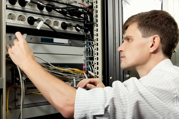 The engineer stand in datacenter near telecomunication equipment - 35690341