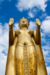 Golden standing Buddha statue inside a temple in Ubonratchathani
