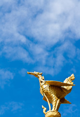 thai style golden bird statue in blue sky