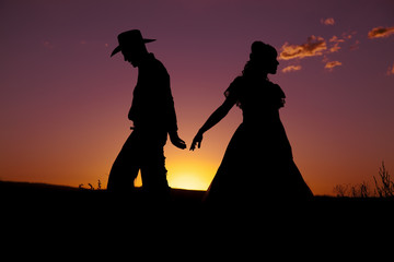 Cowboy couple silhouette walk away