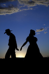 Obraz premium Cowboy couple silhouette walking away