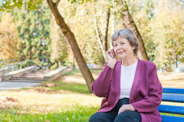 elderly women with phone in autumn park