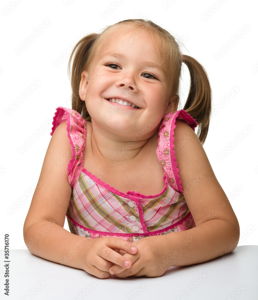 Wall mural happy little girl is sitting at the table