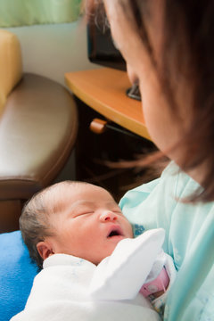 Asian female newborn in mother's arms vertical
