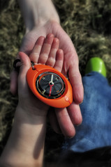 Compass in a child hand with mother supporting palm