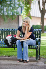 Young female student sitting on bench