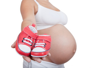 Pregnant woman hold in hand red baby boots