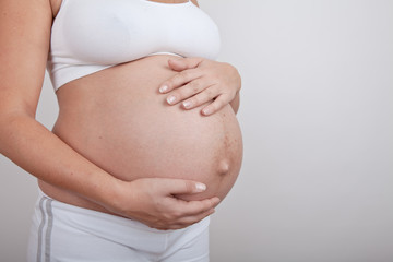 Pregnant woman hold hands on a belly