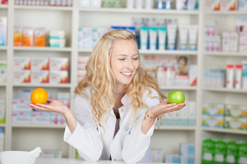 lächelnde apothekerin hält obst in ihren händen
