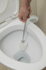 homme nettoyant WC avec brosse
