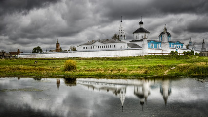 Monastery against the cloudy sky with reflection in lake