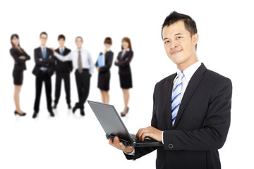 smiling businessman holding laptop and successful business team