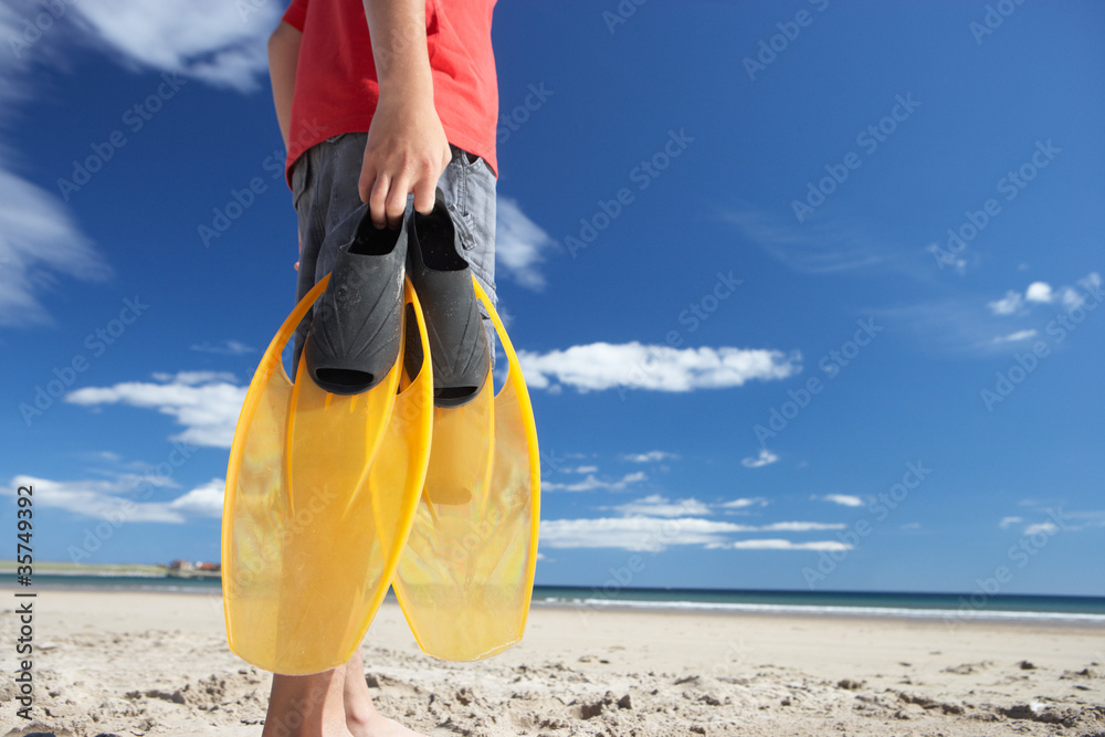 Wall mural Teenage boy on beach with flippers