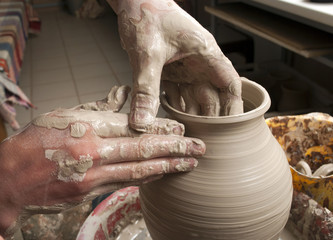 hands of a potter, creating an earthen jar on the circle