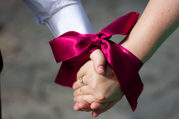 Hands of women and men are associated with red ribbon