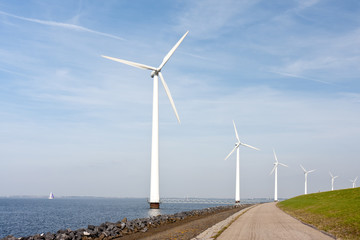 Wind turbines standing along the dyke in the Dutch sea