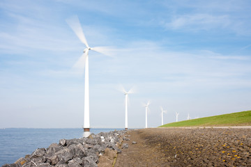 Fototapeta na wymiar Spinning windturbines standing in the sea photographed with long