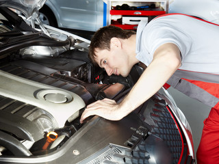 Motor mechanic is checking the engine of a car diligent