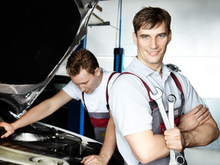 Motor mechanics fixing the engine of a car in a garage