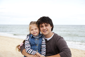 Father and daughter at the beach in fall.