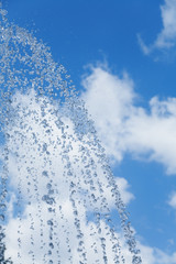 Drops of a clear water against the blue sky with clouds