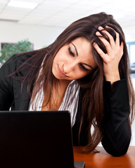 A tired woman in front of a laptop