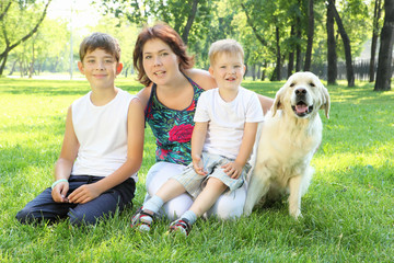 Mother and her two sons in the park with a dog