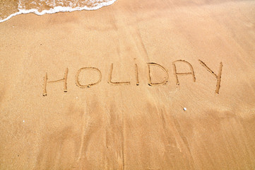 Holiday text written on the beach sand