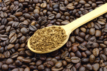 Ground coffee in wooden spoon on a coffee beans background