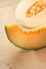 Cantaloupe melon slice and one half on wooden table