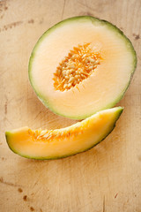 Cantaloupe melon slice and one half on wooden table