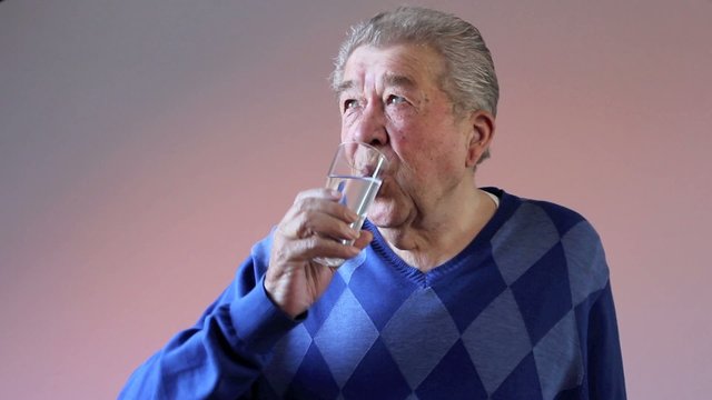 Senior trinkt durstig ein Glas Wasser