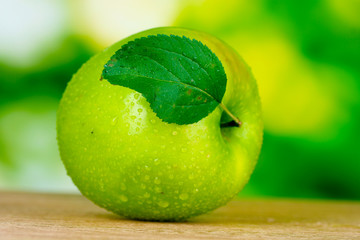 Healthy ripe dropped apple on wooden table outside